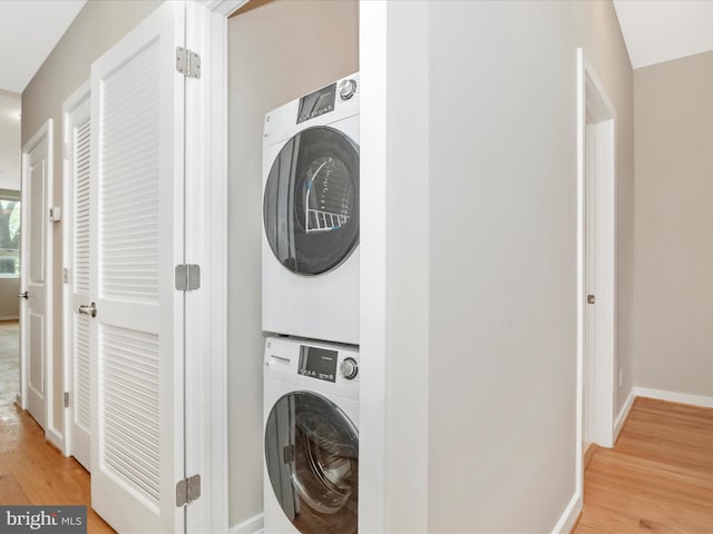 laundry area featuring light hardwood / wood-style floors and stacked washer and clothes dryer