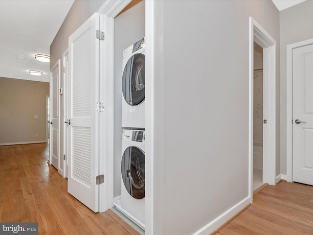 laundry room with light hardwood / wood-style floors and stacked washer / drying machine