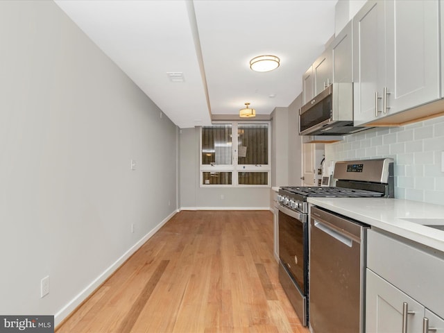 kitchen featuring light wood-type flooring, stainless steel appliances, and tasteful backsplash