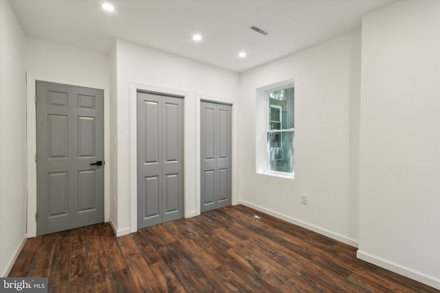 unfurnished bedroom featuring two closets and dark hardwood / wood-style floors