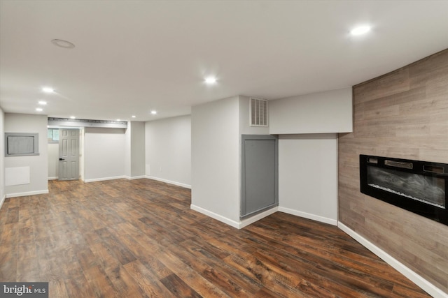 basement featuring a large fireplace and dark wood-type flooring