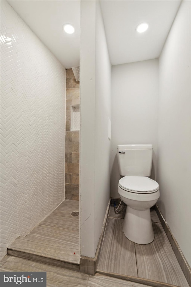 bathroom with tiled shower and toilet