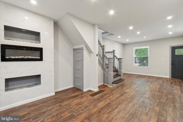 unfurnished living room with a high end fireplace and dark wood-type flooring