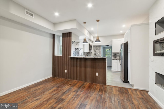 kitchen featuring kitchen peninsula, stainless steel fridge, hardwood / wood-style flooring, and white cabinetry