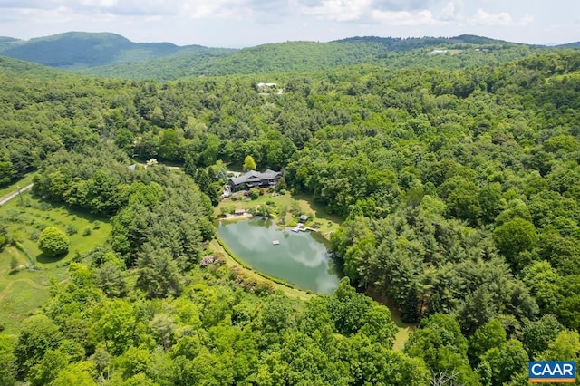 drone / aerial view with a water and mountain view and a view of trees