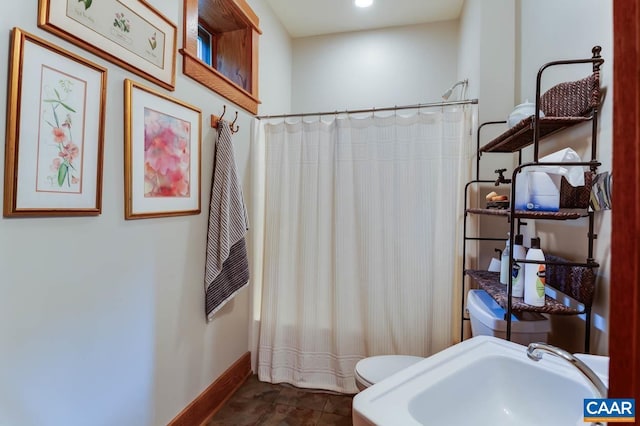 full bath featuring baseboards, a shower with shower curtain, a sink, and toilet