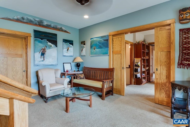 living area featuring light carpet and a ceiling fan