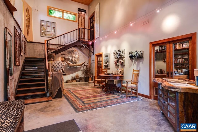 interior space featuring concrete flooring, a high ceiling, and stairway