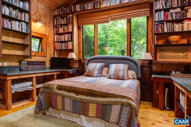 bedroom with wood walls, multiple windows, wood finished floors, and built in study area