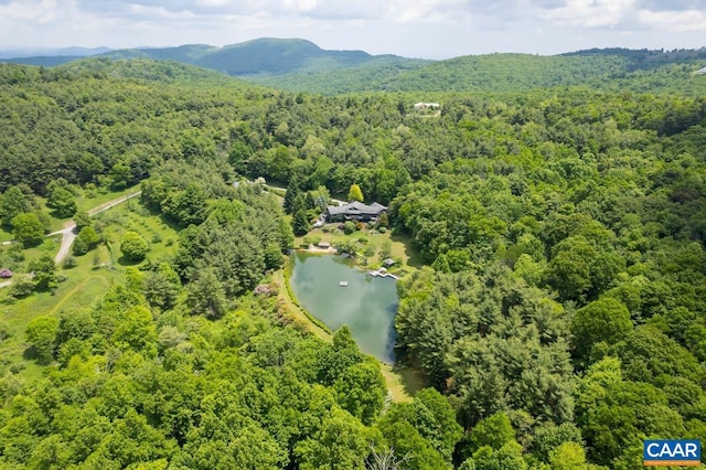 drone / aerial view with a water and mountain view and a view of trees