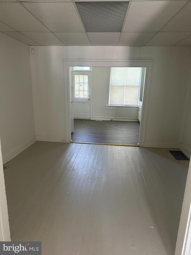 empty room with wood-type flooring and a paneled ceiling