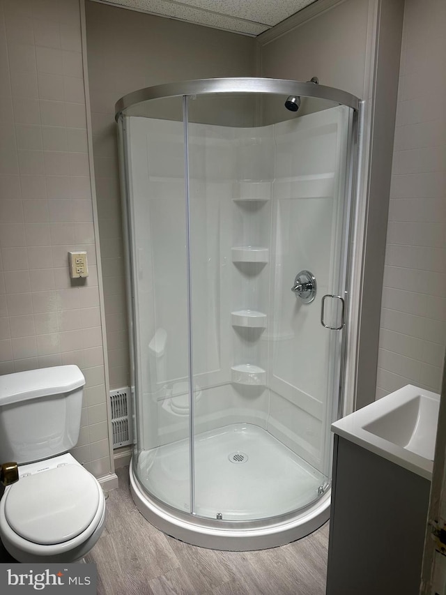 bathroom featuring toilet, a shower with shower door, and tile walls