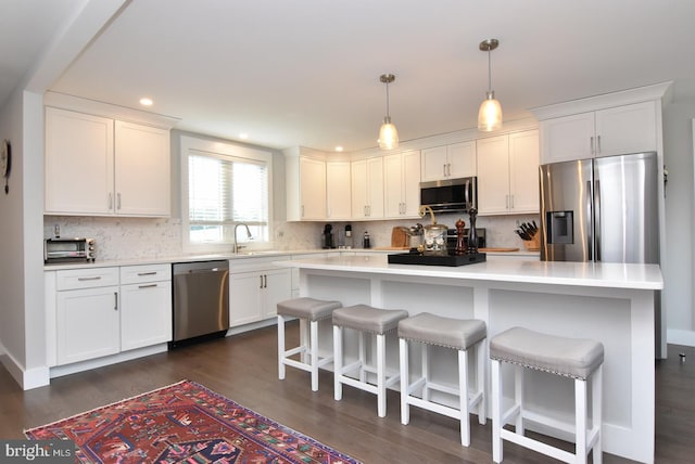 kitchen featuring white cabinets, a center island, hanging light fixtures, and appliances with stainless steel finishes