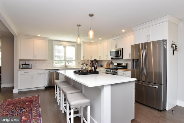 kitchen with white cabinets, appliances with stainless steel finishes, dark hardwood / wood-style flooring, and a kitchen island