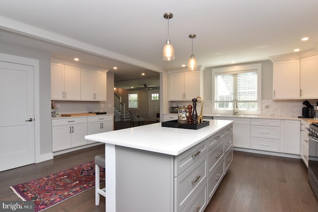 kitchen featuring a kitchen bar, white cabinetry, a kitchen island, and dark wood-type flooring