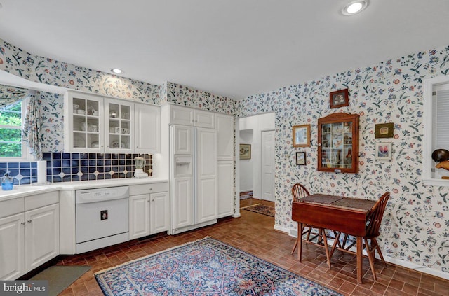 kitchen with tasteful backsplash, white cabinetry, and white dishwasher