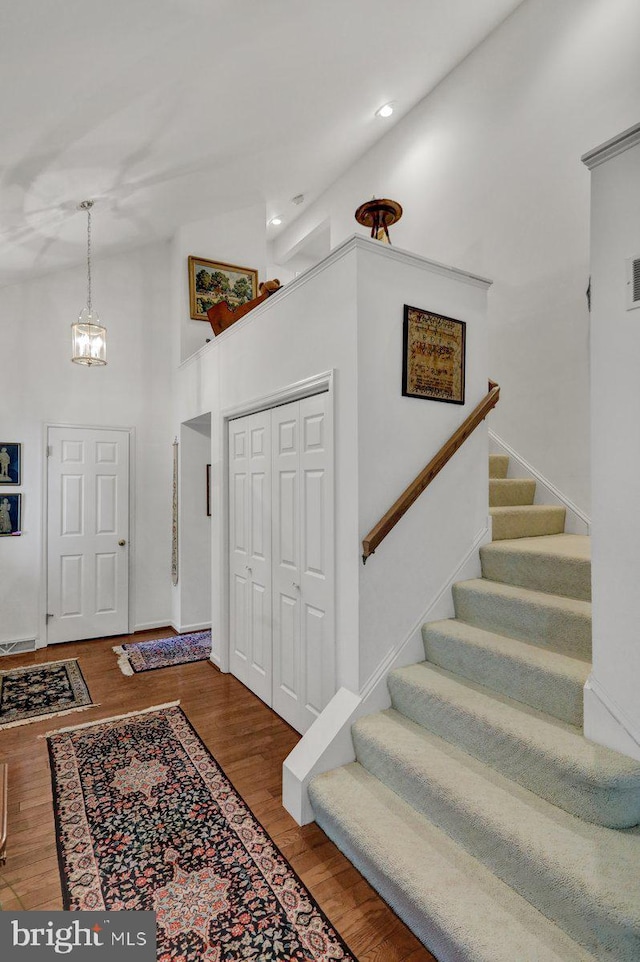 entryway with hardwood / wood-style floors, high vaulted ceiling, and a notable chandelier