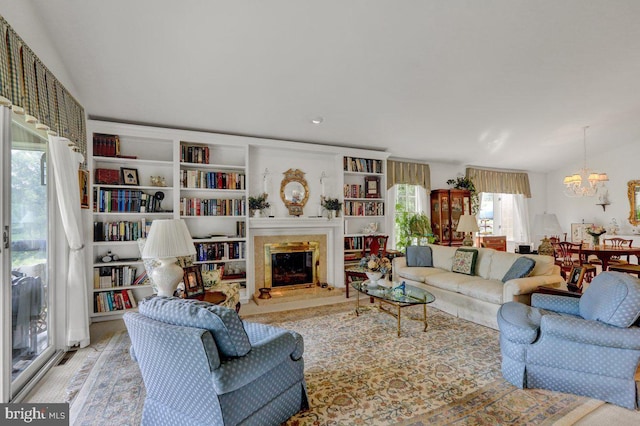 living room featuring a premium fireplace, vaulted ceiling, and an inviting chandelier