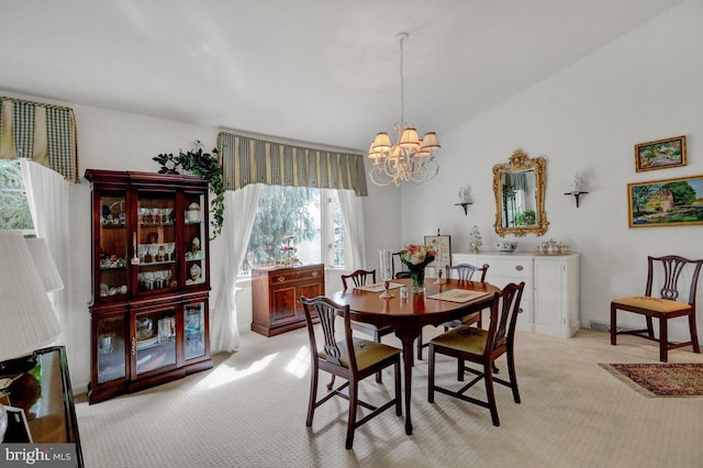 carpeted dining area with an inviting chandelier and lofted ceiling