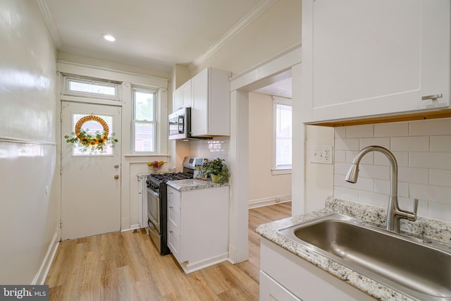 kitchen featuring backsplash, stainless steel appliances, sink, light hardwood / wood-style flooring, and white cabinets