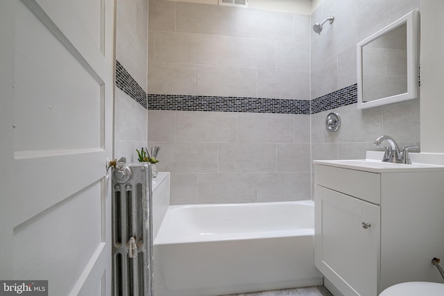 bathroom featuring vanity, tiled shower / bath, and tile walls