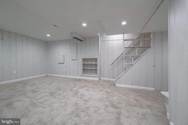 basement with light colored carpet and wooden walls