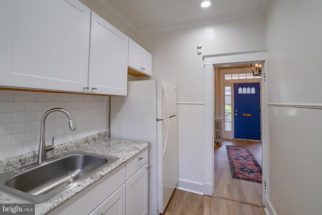 kitchen with white cabinets, sink, light hardwood / wood-style flooring, tasteful backsplash, and white fridge