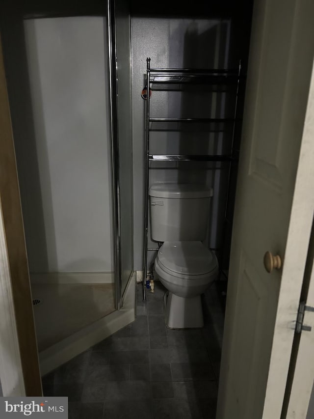 bathroom with a shower, tile patterned floors, and toilet