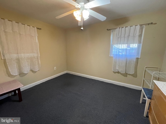 spare room with dark colored carpet and ceiling fan