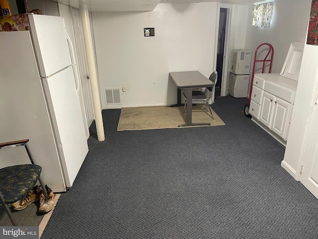 basement with dark carpet and white refrigerator