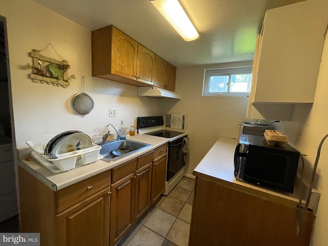 kitchen featuring white electric range oven, light tile patterned floors, and sink