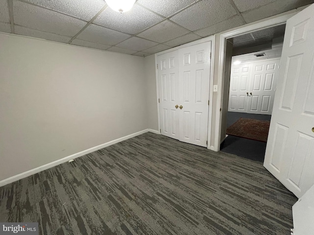 unfurnished bedroom featuring a paneled ceiling, a closet, and dark wood-type flooring