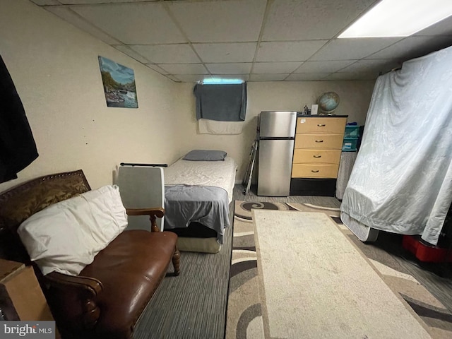 carpeted bedroom featuring stainless steel refrigerator and a paneled ceiling