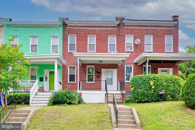 townhome / multi-family property with covered porch and a front lawn