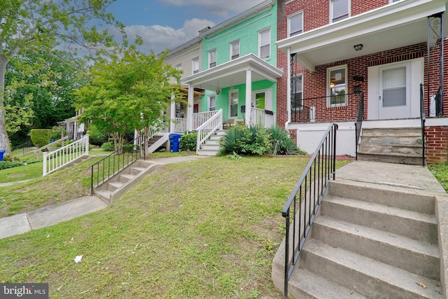 multi unit property featuring covered porch and a front yard