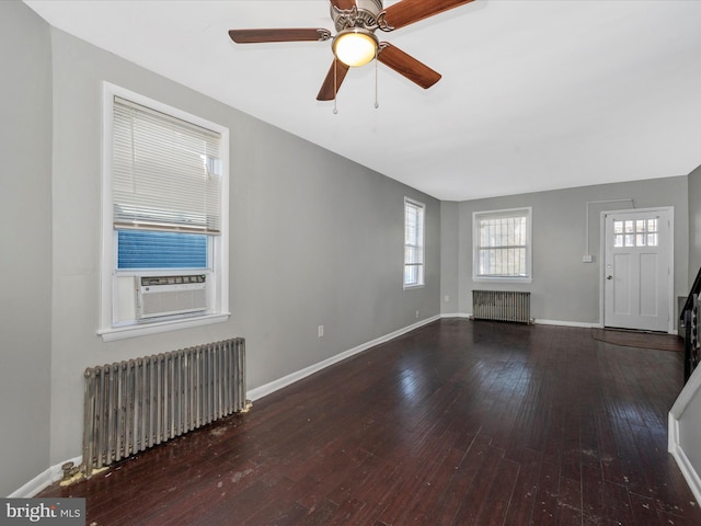 unfurnished living room featuring radiator heating unit, hardwood / wood-style flooring, cooling unit, and ceiling fan