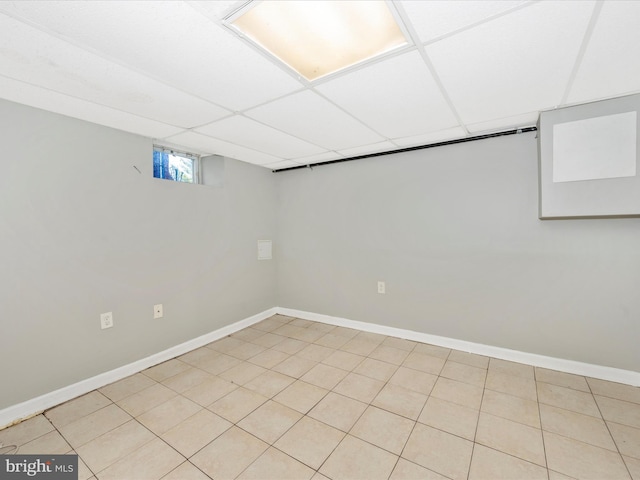 basement with light tile patterned floors and a drop ceiling