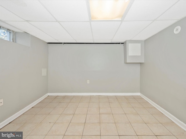 basement featuring a paneled ceiling and light tile patterned flooring