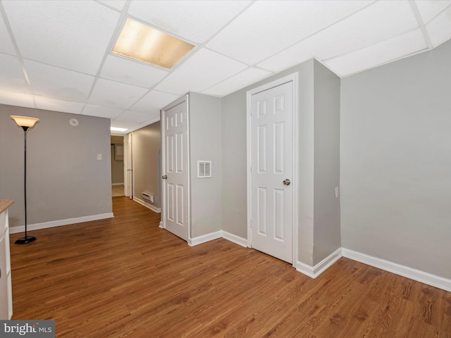 basement featuring a paneled ceiling and hardwood / wood-style floors