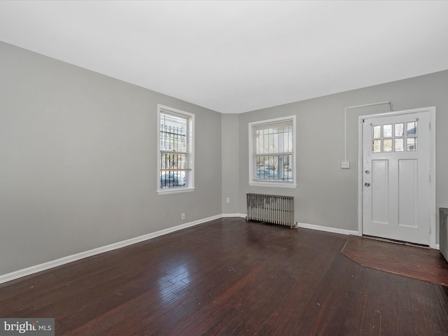 entrance foyer with dark hardwood / wood-style flooring and radiator heating unit