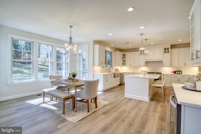 dining area featuring a notable chandelier, sink, and light hardwood / wood-style flooring