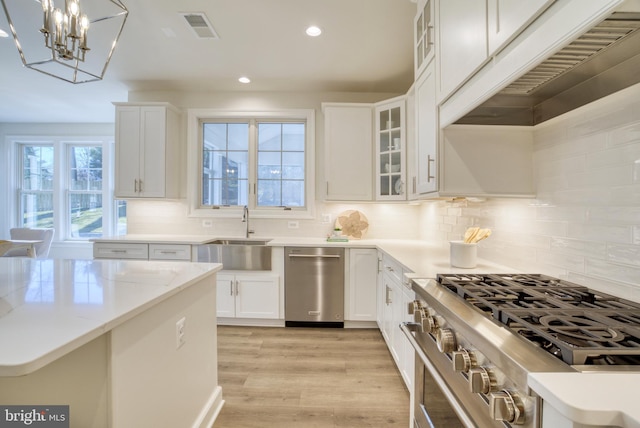 kitchen featuring decorative backsplash, high end stainless steel range oven, pendant lighting, light hardwood / wood-style floors, and white cabinetry