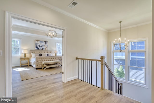 bedroom with light hardwood / wood-style flooring, ornamental molding, and a notable chandelier