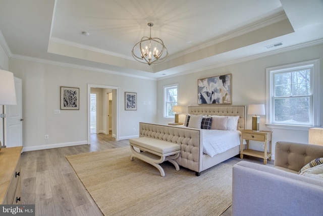 bedroom with light hardwood / wood-style floors, a raised ceiling, crown molding, and an inviting chandelier