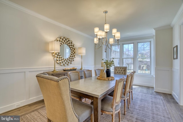 dining room with wood-type flooring, ornamental molding, and a chandelier