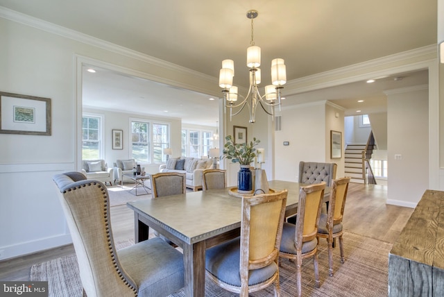 dining room with a chandelier, ornamental molding, and hardwood / wood-style flooring