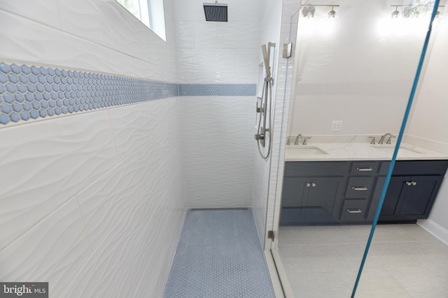 bathroom with tile patterned flooring, a tile shower, and vanity