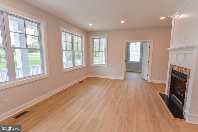 unfurnished living room with a wealth of natural light, a fireplace, and light wood-type flooring