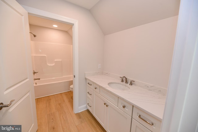 full bathroom featuring tub / shower combination, vanity, hardwood / wood-style flooring, toilet, and lofted ceiling