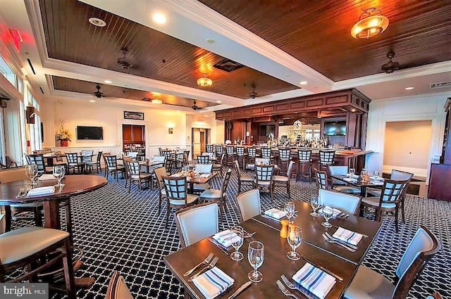 dining room with a raised ceiling, ceiling fan, ornamental molding, and wood ceiling